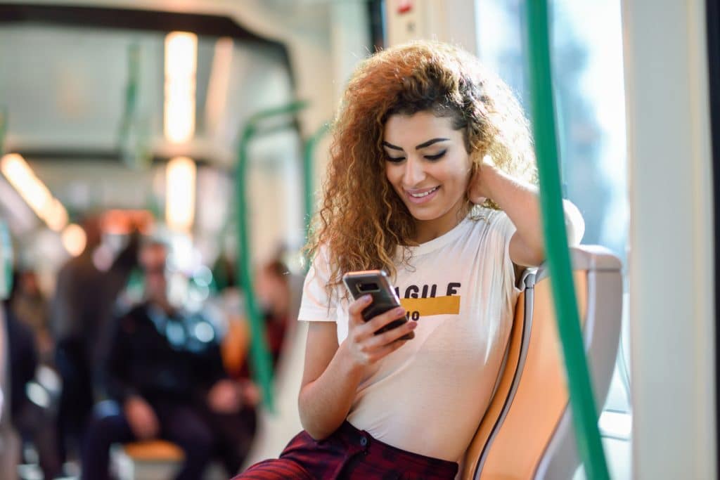 woman inside subway train looking at her smart phone