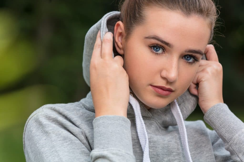 young woman with blue eyes outside wearing grey hoody